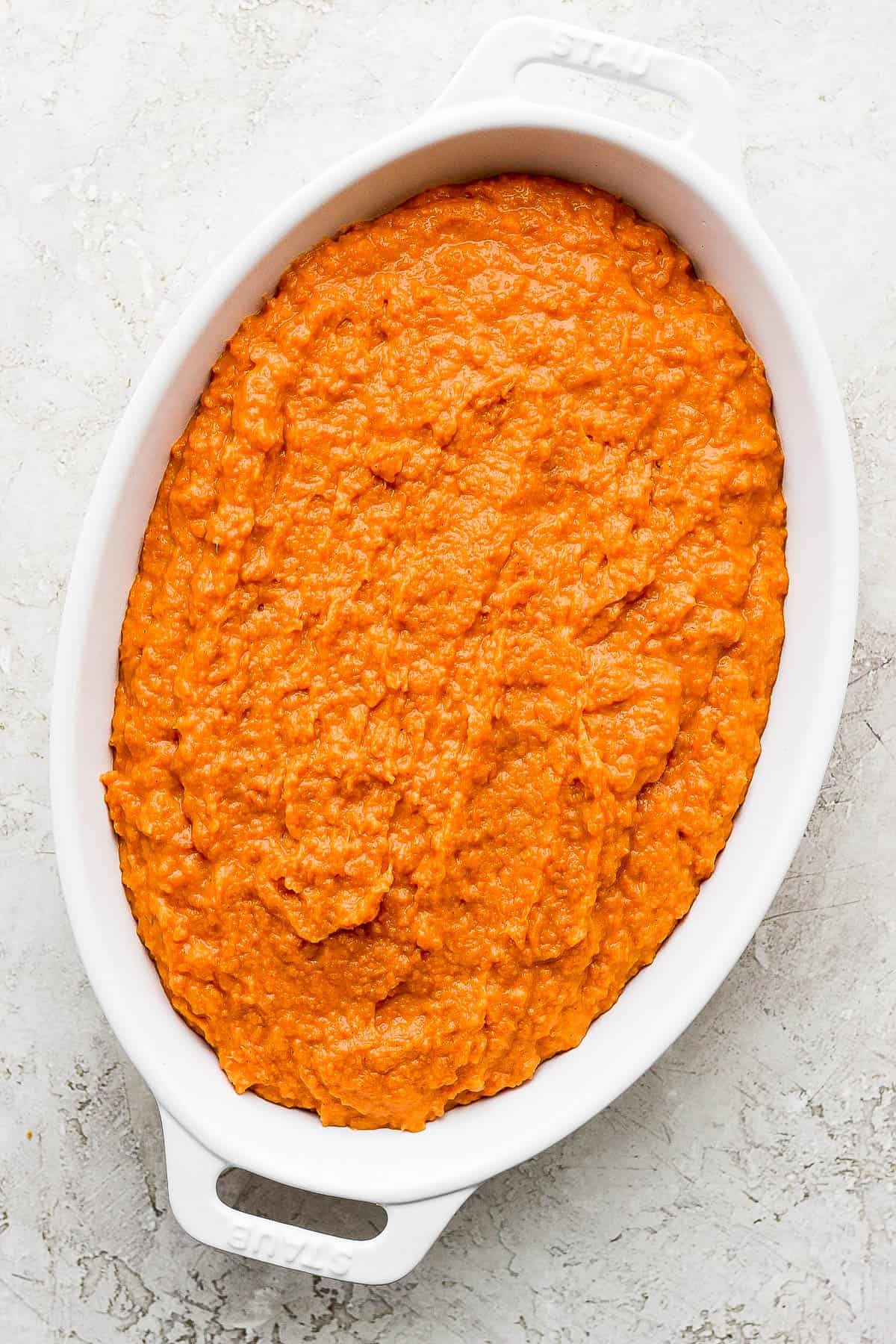 The blended sweet potato mix evenly spread into an oval casserole dish.