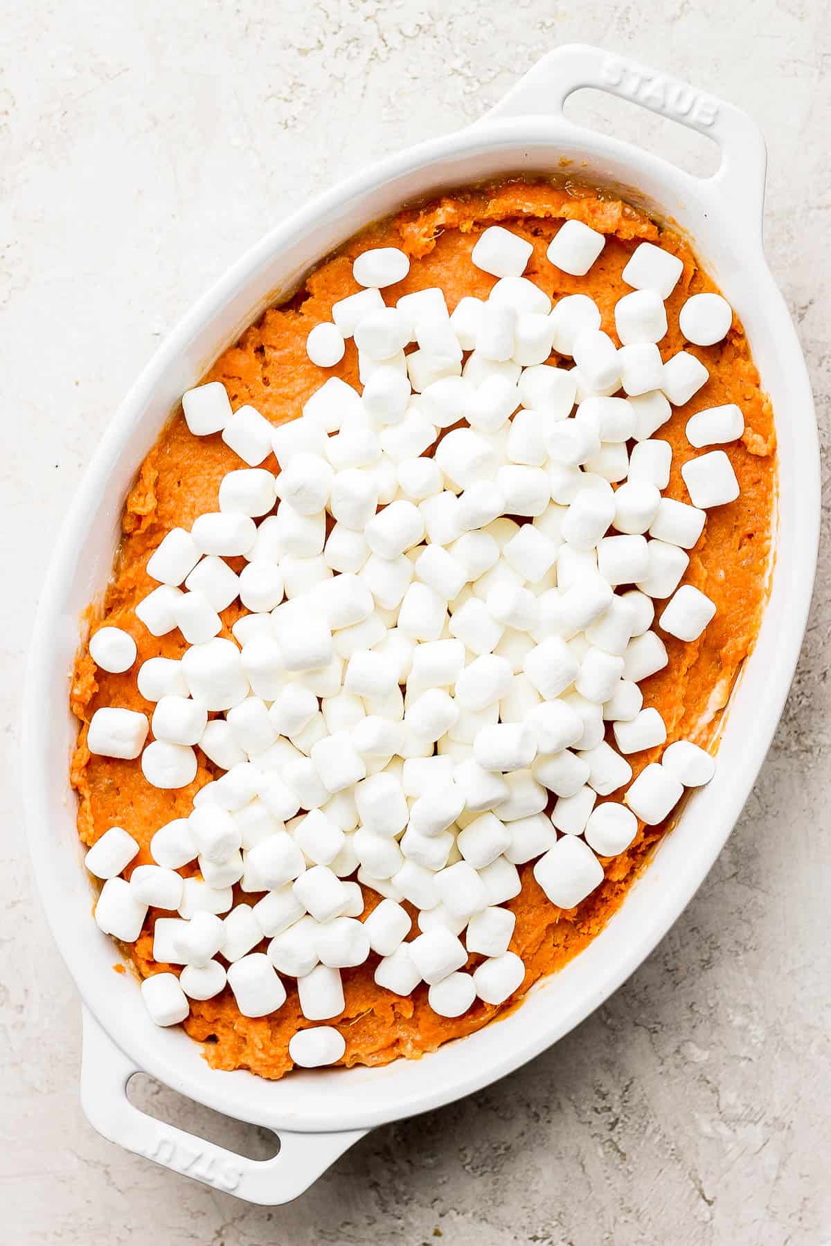 Mini marshmallows spread evenly on top of the sweet potato mixture in the casserole dish.