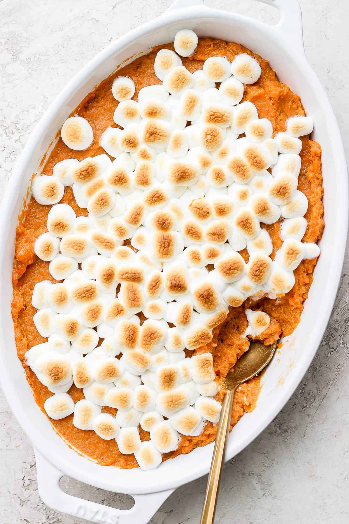 A fully cooked sweet potato casserole topped with mini marshmallows that are slightly browned due to baking. 