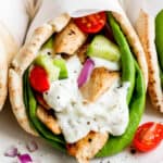 Close up shot of a chicken gyro with tomatoes, cucumbers and red onion.