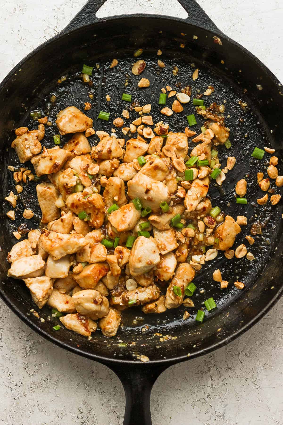 Sauce, peanuts, and sesame oil added to the pan.