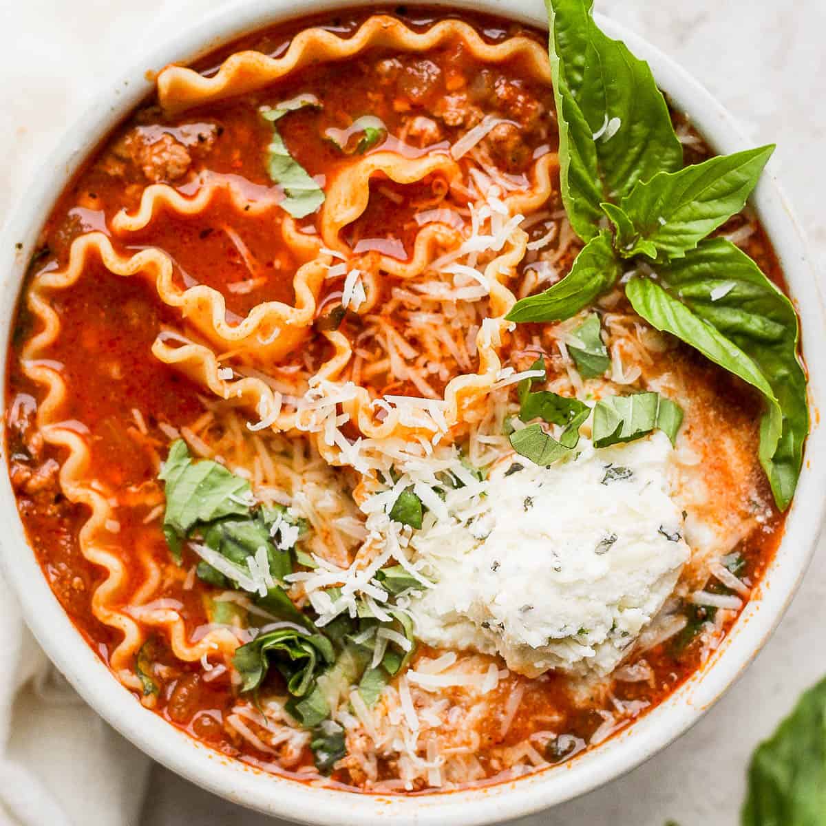 Bowl of homemade lasagna soup with ricotta, fresh basil and parmesan cheese.