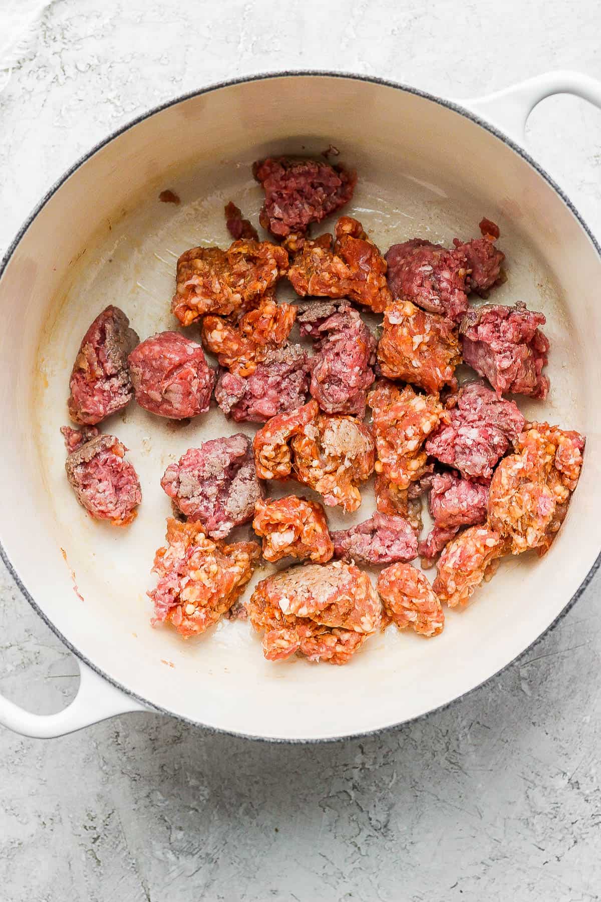 Ground beef and Italian sausage in a dutch oven.