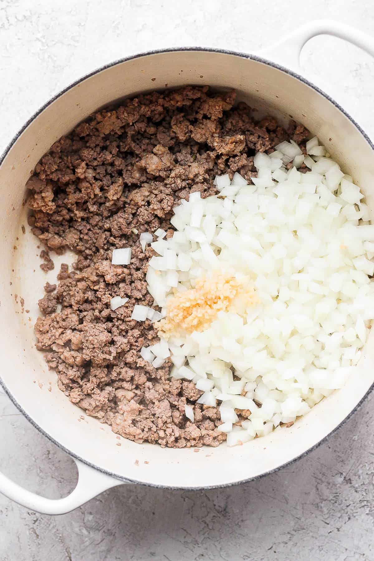 Browned beef and sausage in the pot with onion and garlic.