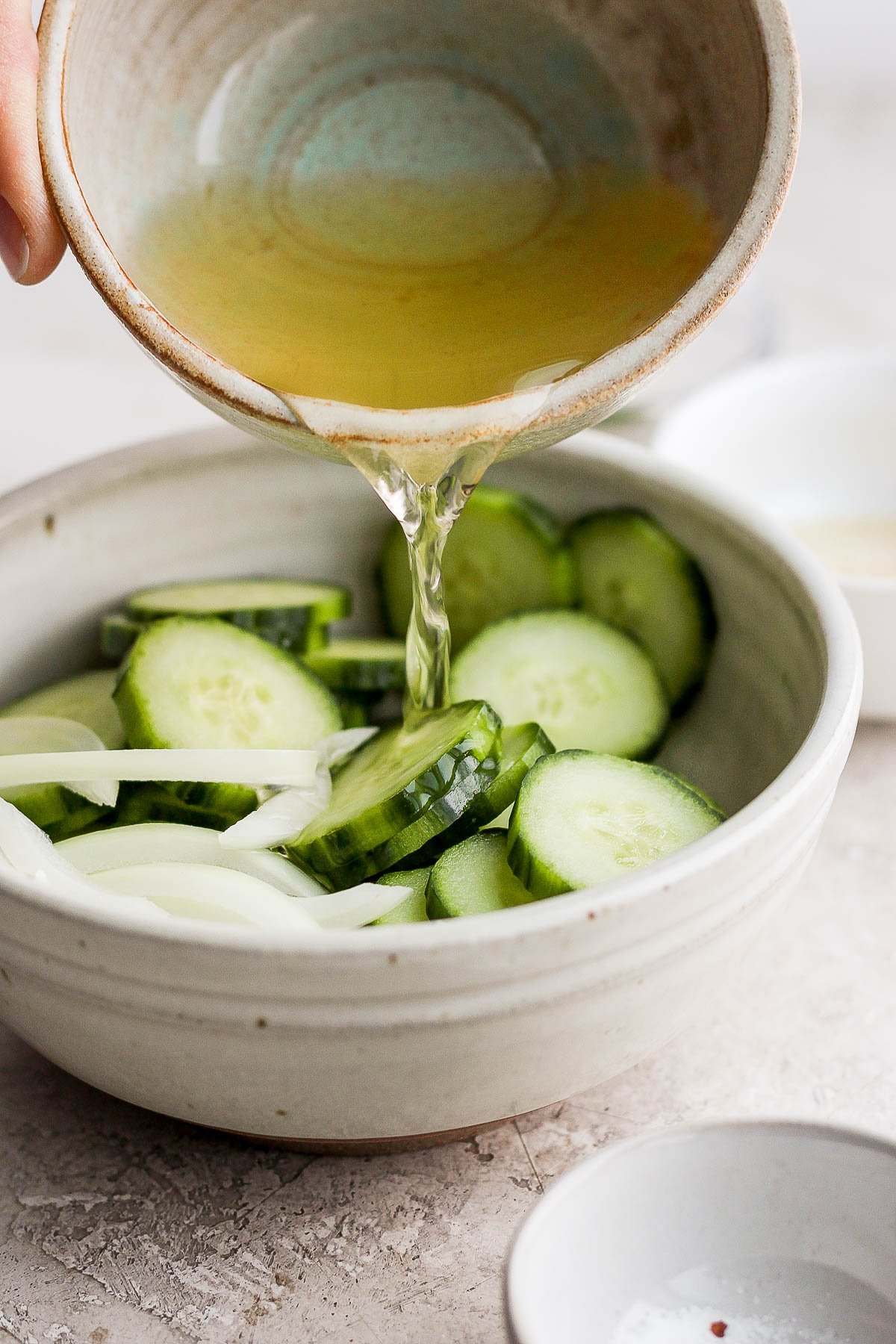 The vinegar mixture being poured into the cucumber and onion mixture. 