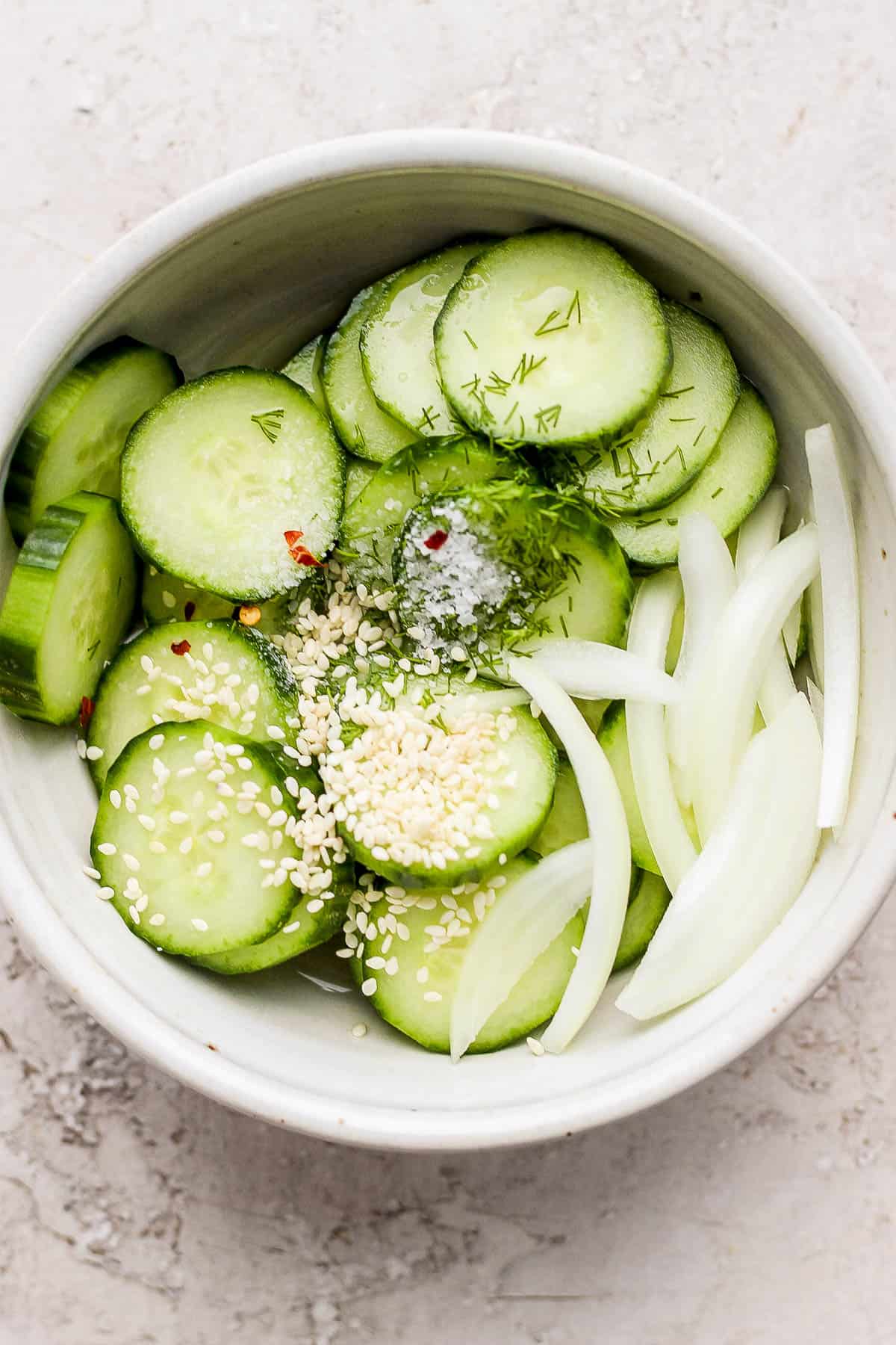 Cucumbers, onion, vinegars, salt, sesame seeds, and red pepper flakes all in the same bowl. 