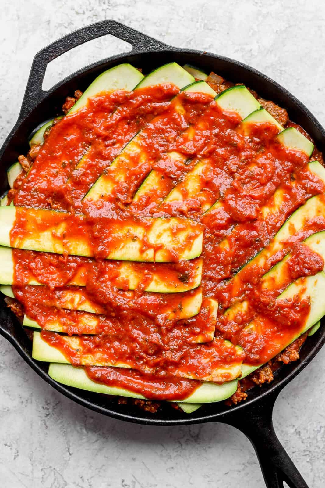 A layer of meat sauce over the top of zucchini to make zucchini lasagna with meat sauce.