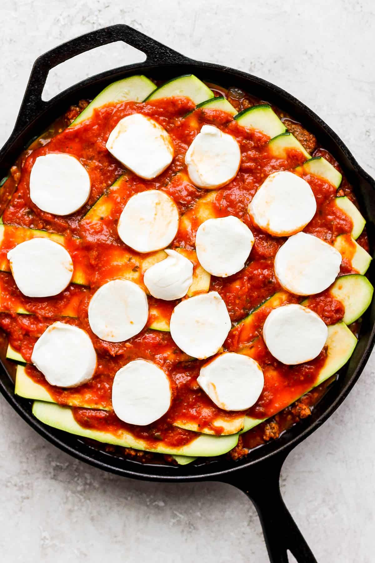 About 15 slices of fresh mozzarella on top of the meat sauce layer of the zucchini lasagna. 