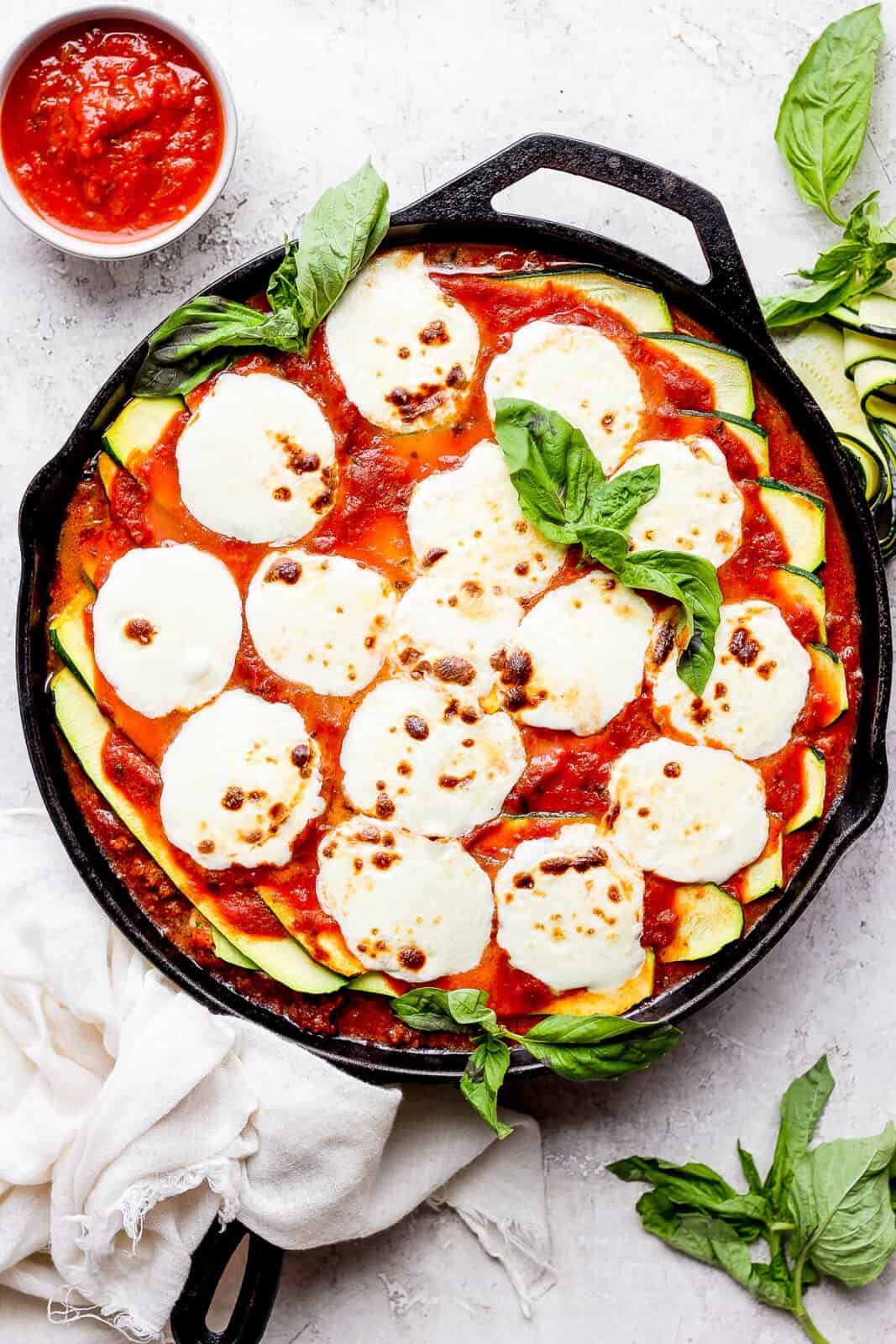 Zucchini lasagna with meat sauce topped with fresh mozzarella and garnished with fresh basil.
