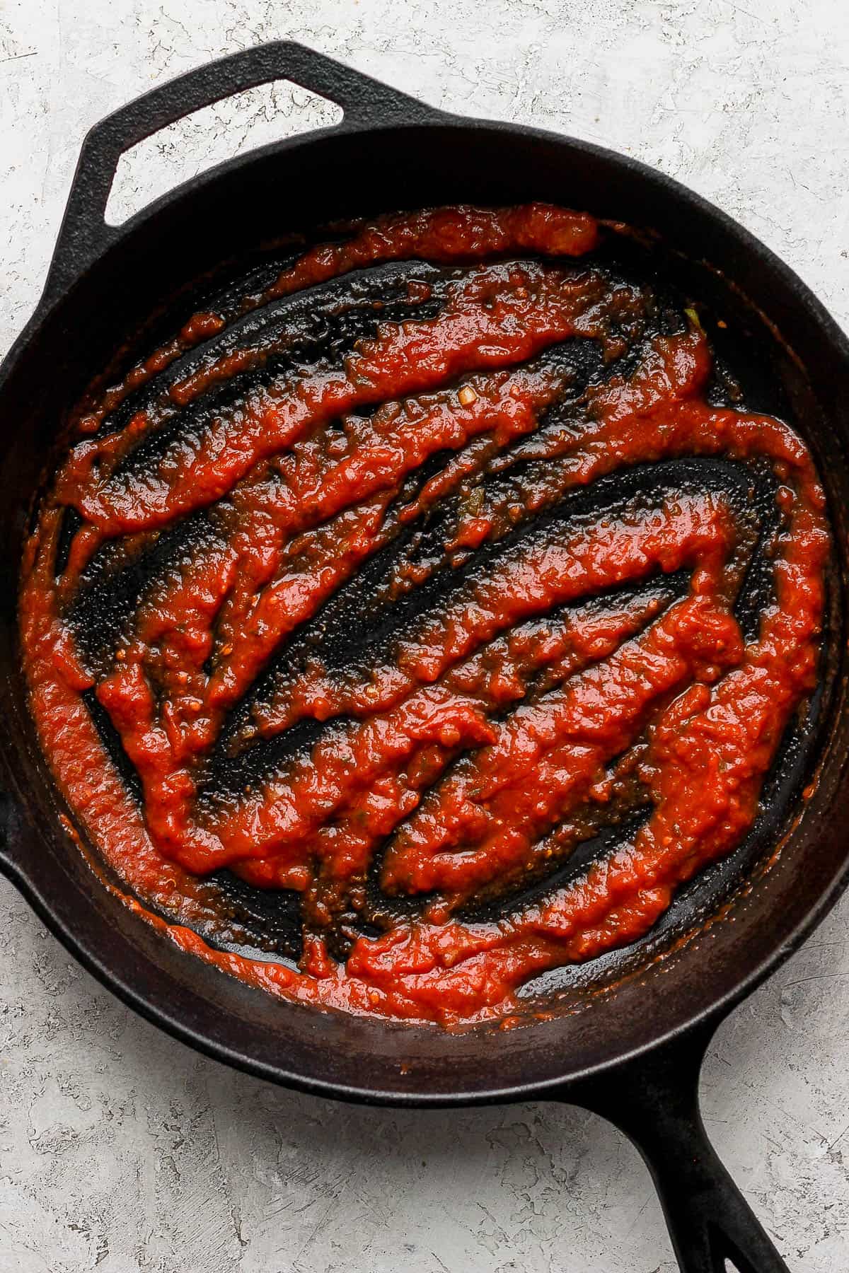 A thin layer of meat mixture on the bottom of a cast iron skillet to make zucchini lasagna with meat sauce.