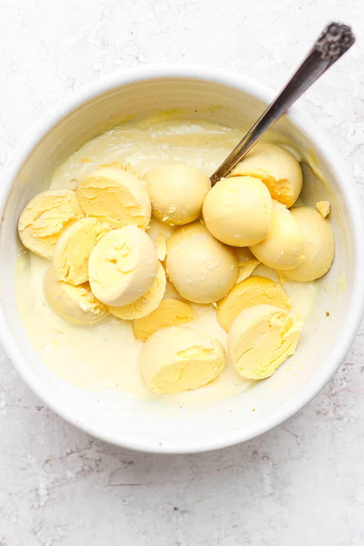 The egg yolks being added to the filling ingredients in a bowl with a spoon.