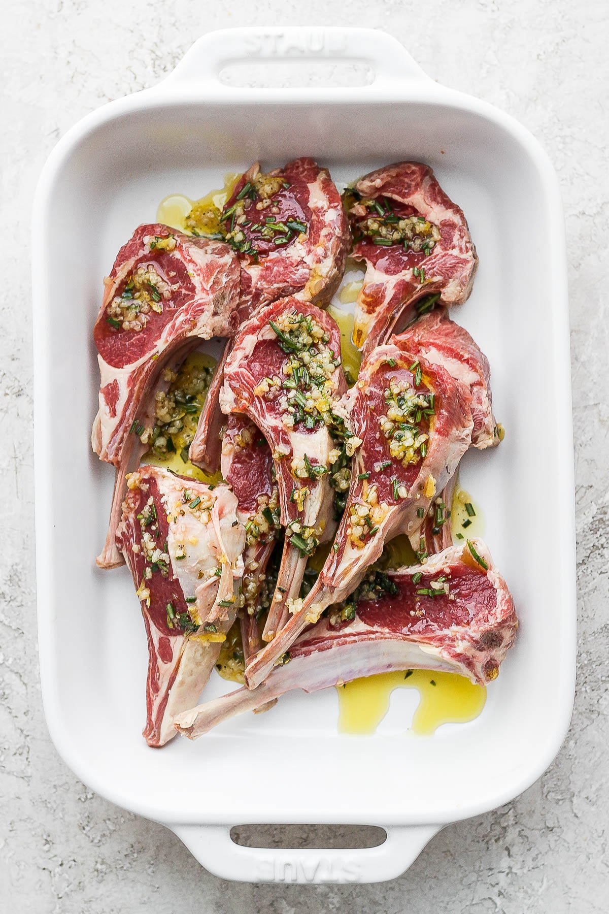 Lamb chops marinating in a baking dish.