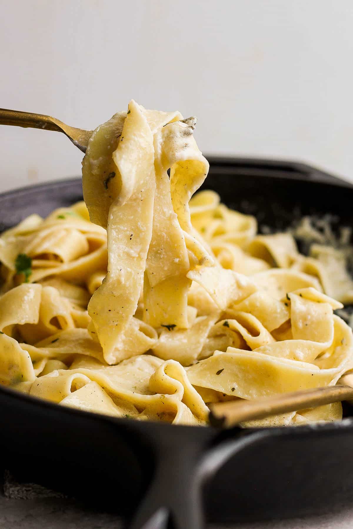 A fork lifting the noodles out of the pan.