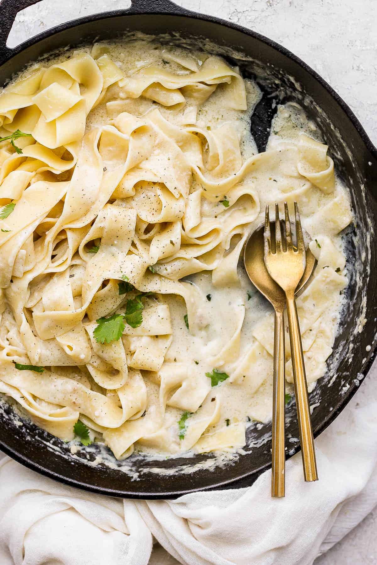 The noodles and alfredo sauce mixed completely in the pan with a spoon and fork.