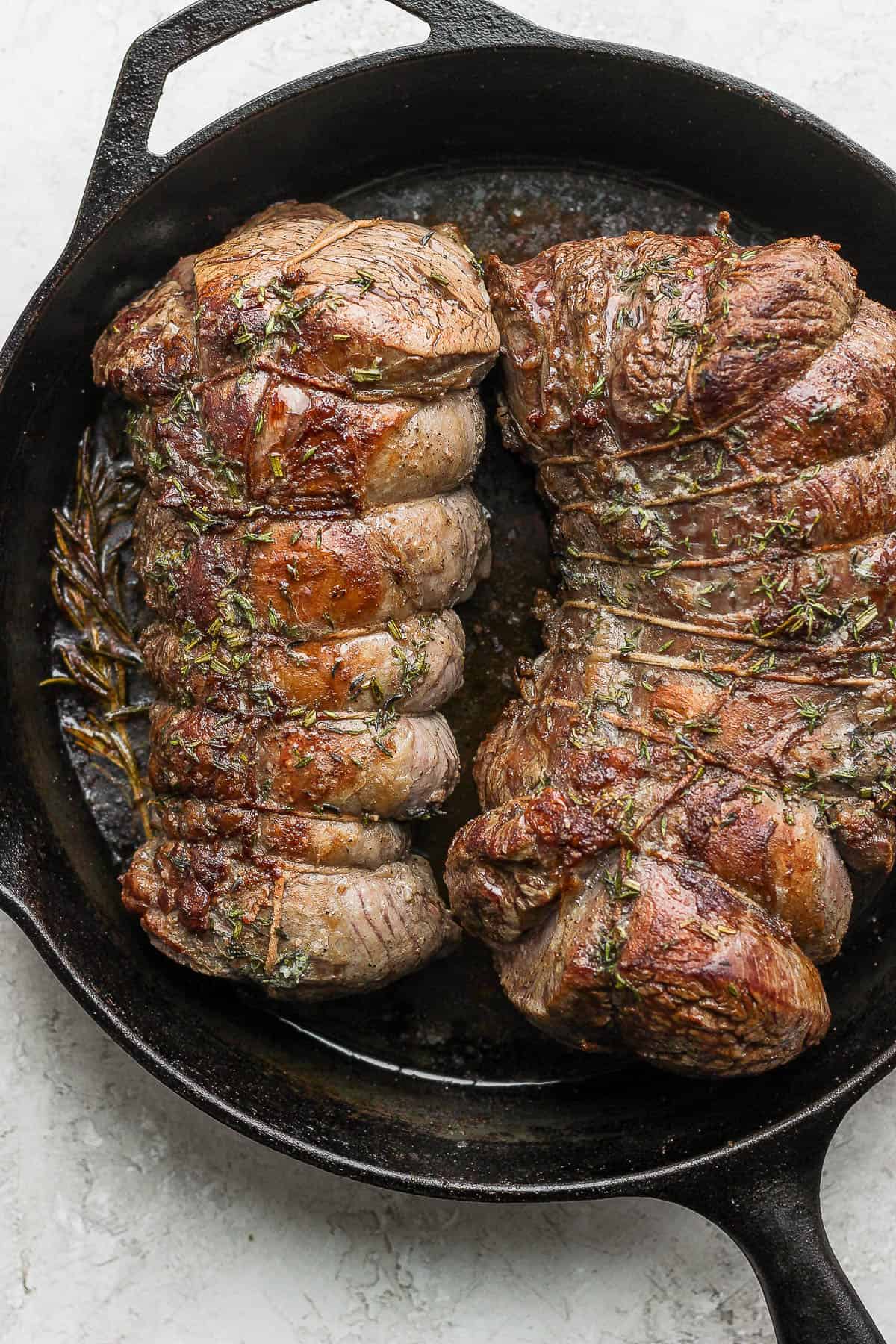 Fully cooked beef tenderloin in a large cast iron skillet.