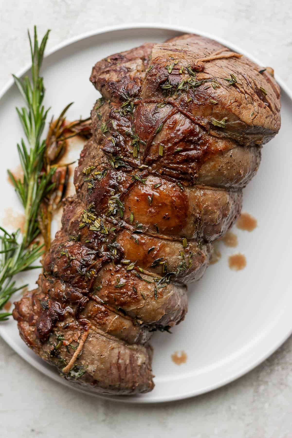 A beef tenderloin on a white plate.