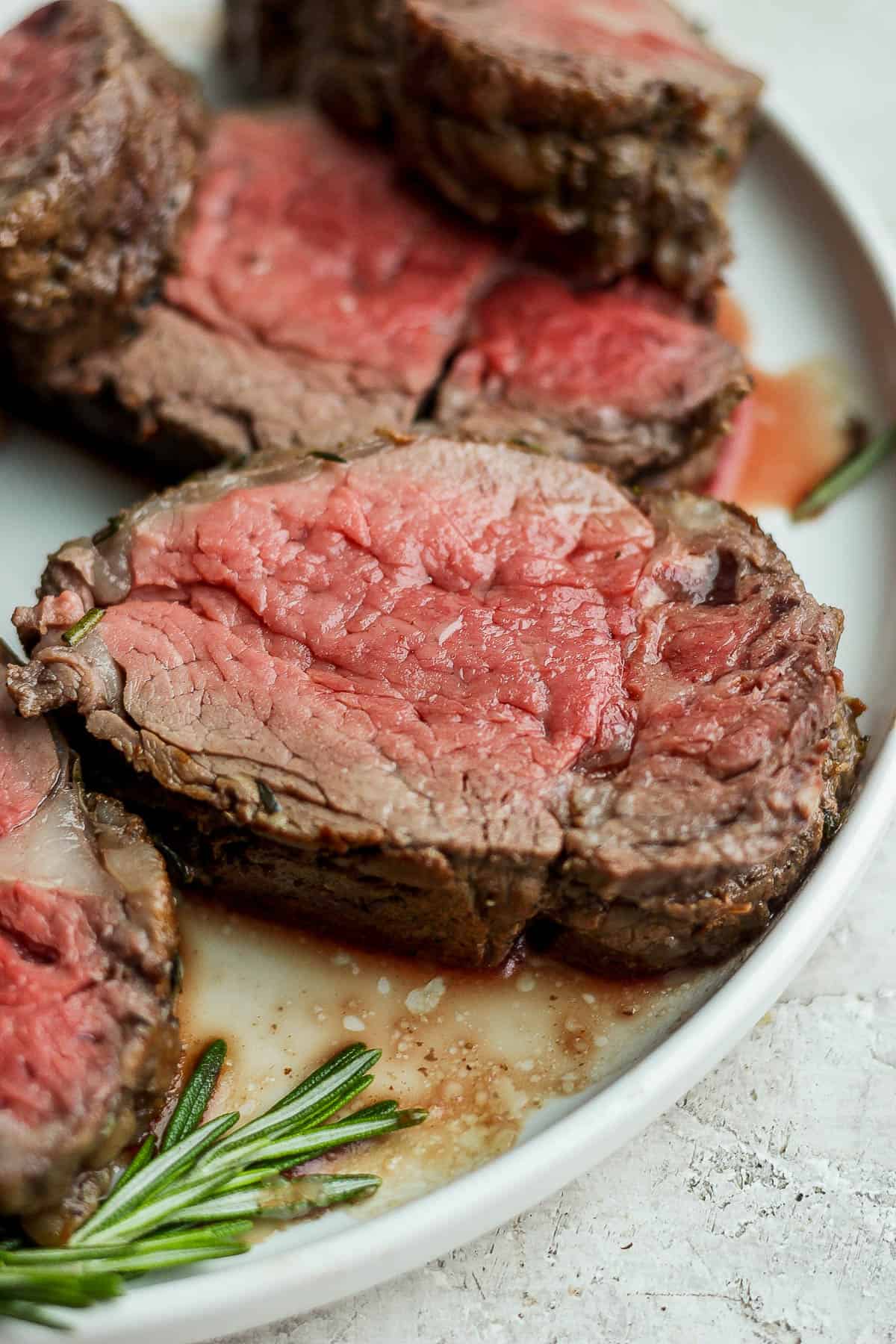 Slices of beef tenderloin on a white plate.