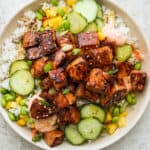 A salmon rice bowl with cucumbers, mango and siracha mayo.