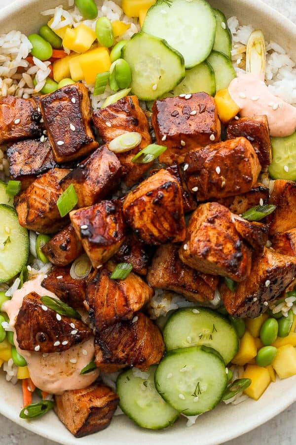 A salmon rice bowl with cucumbers, mango and siracha mayo.