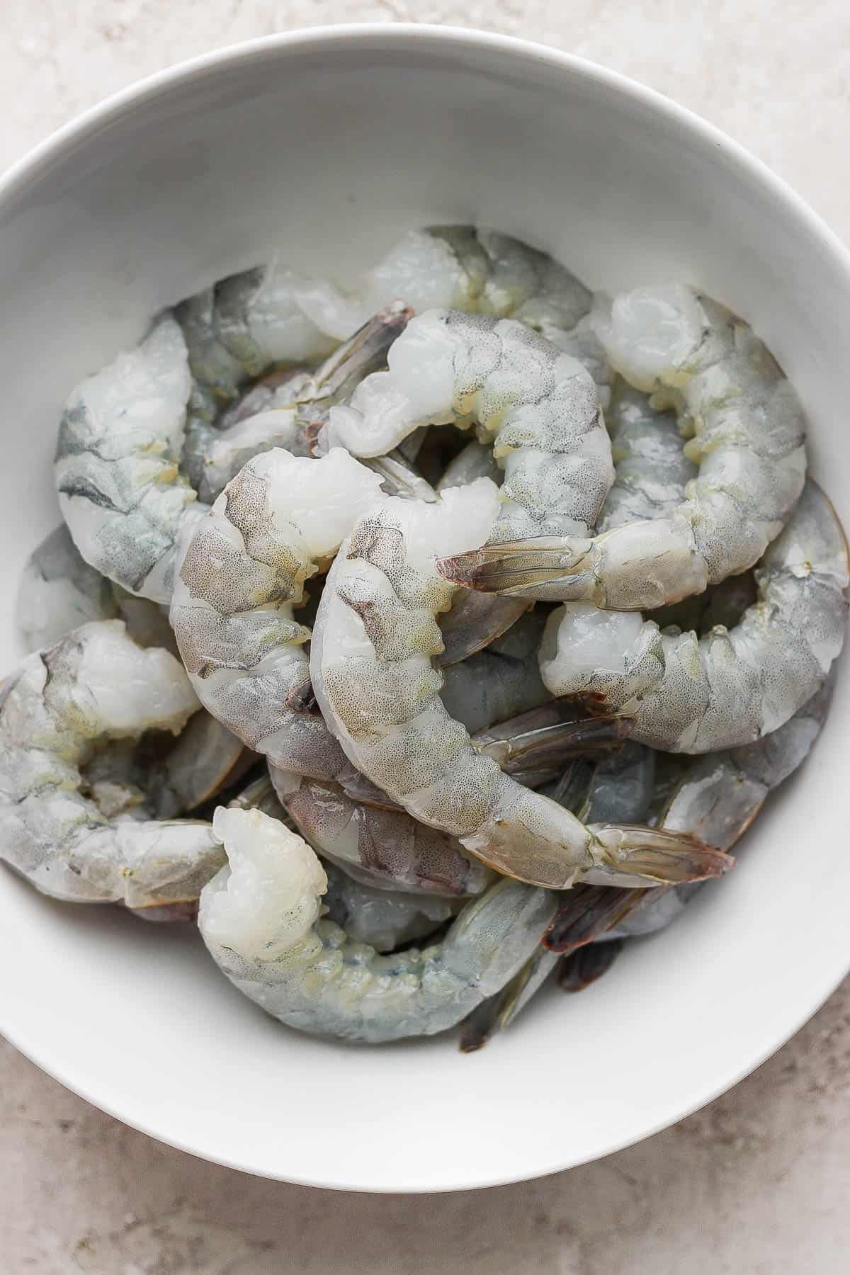 Raw, tail-on jumbo shrimp in a bowl.