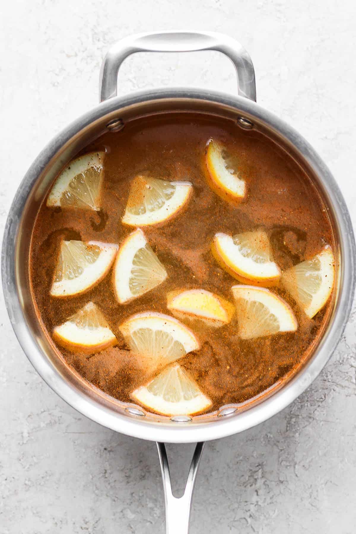 A stock pot filled with water with lemon wedges, Old Bay Seasoning, and salt mixed into the water.