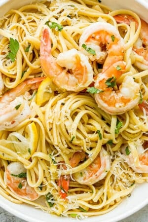 Bowl of shrimp scampi pasta garnished with fresh parsley and parmesan cheese.