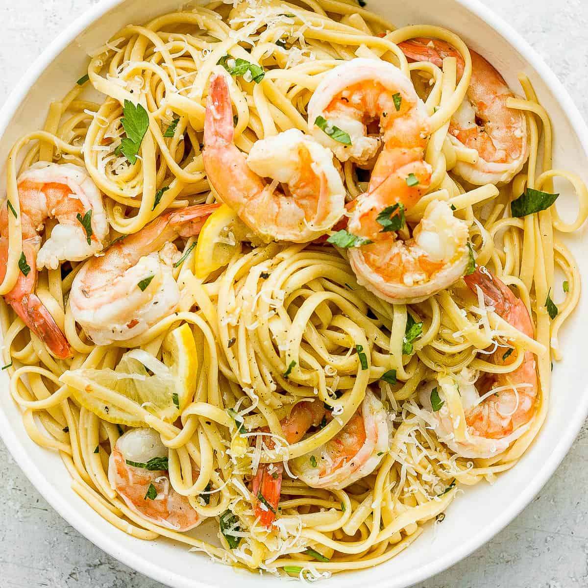 Bowl of shrimp scampi pasta garnished with fresh parsley and parmesan cheese.