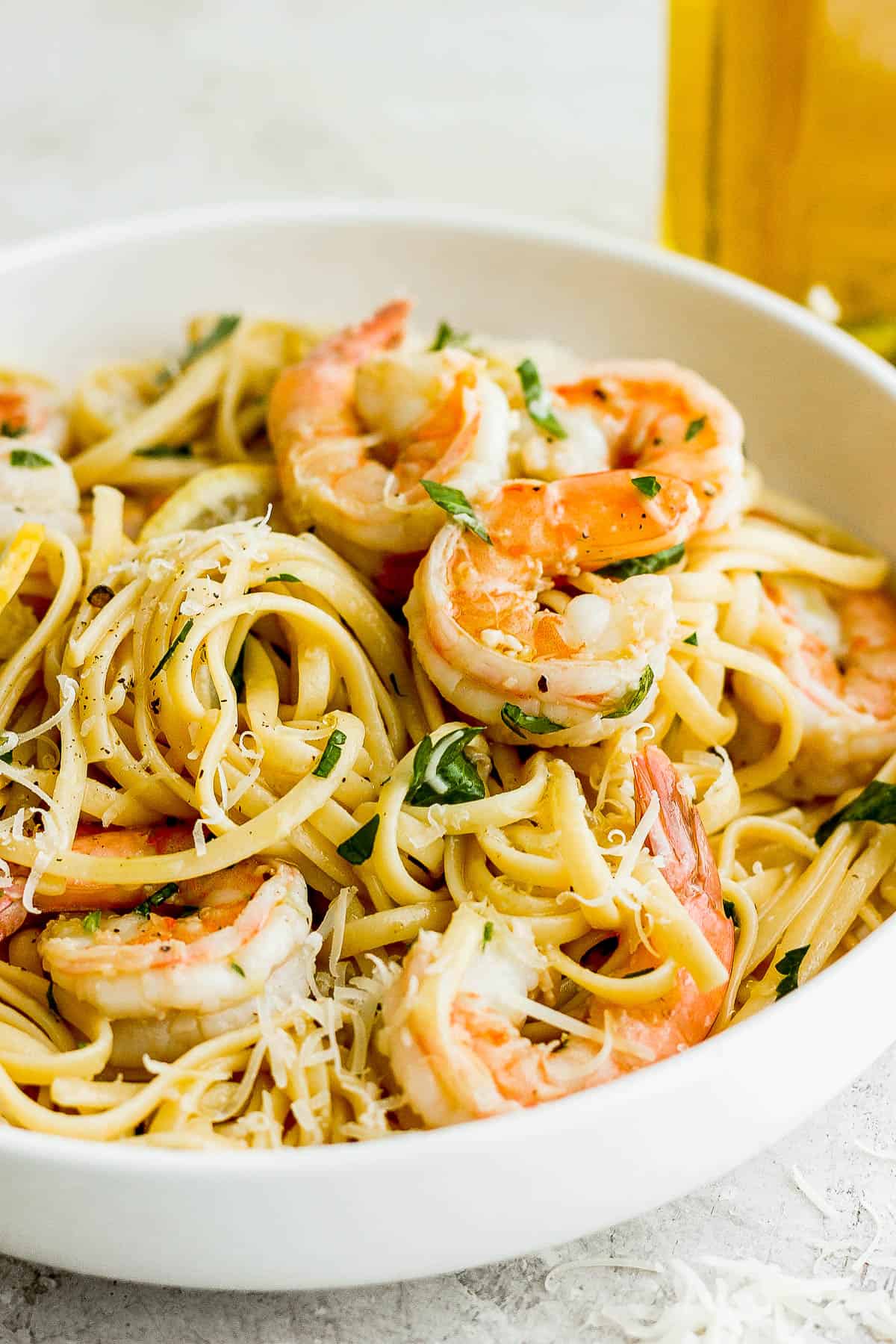 Shrimp scampi tossed in a bowl with linguine noodles.