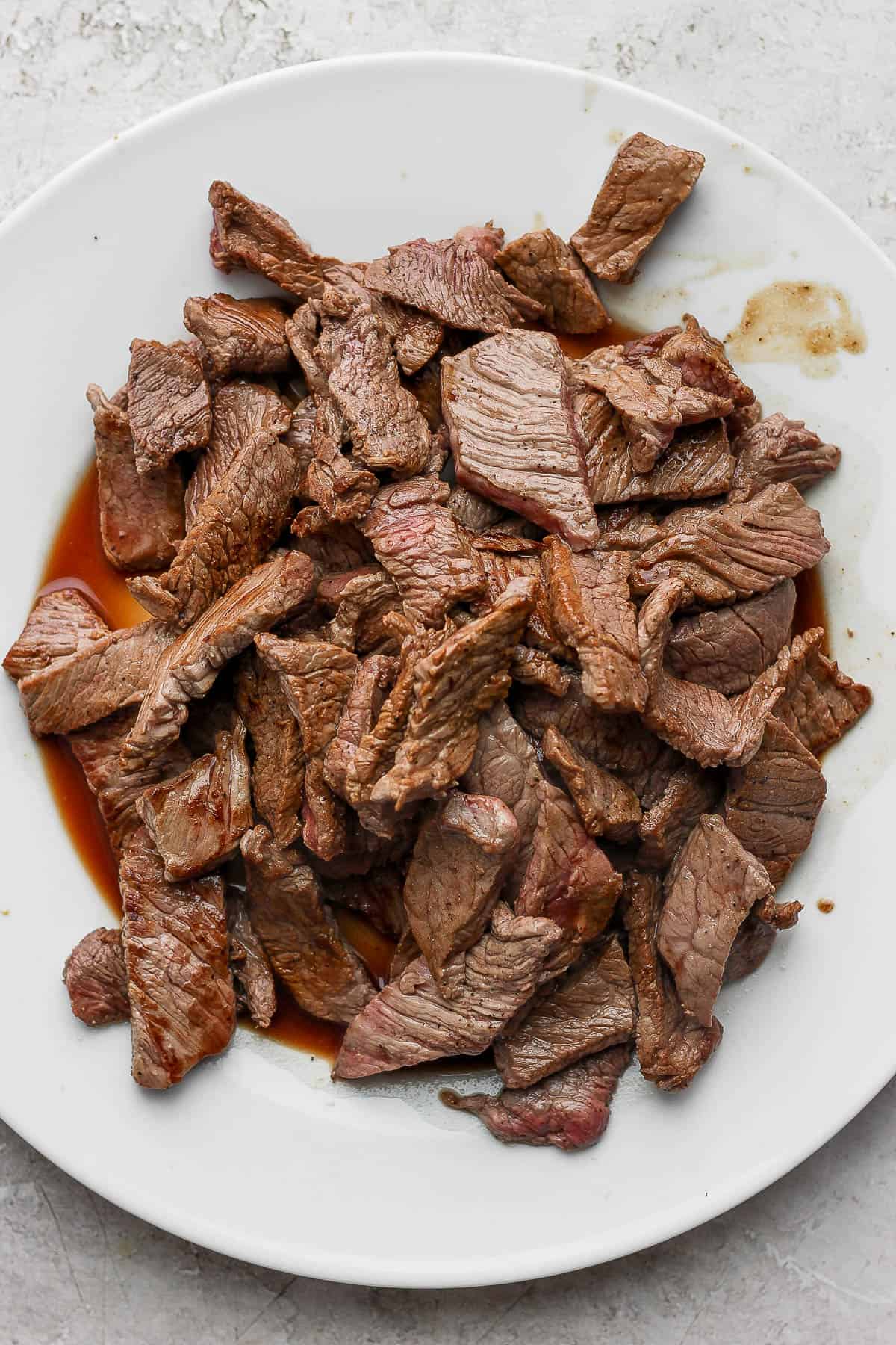 A plate full of seared sirloin steak strips.