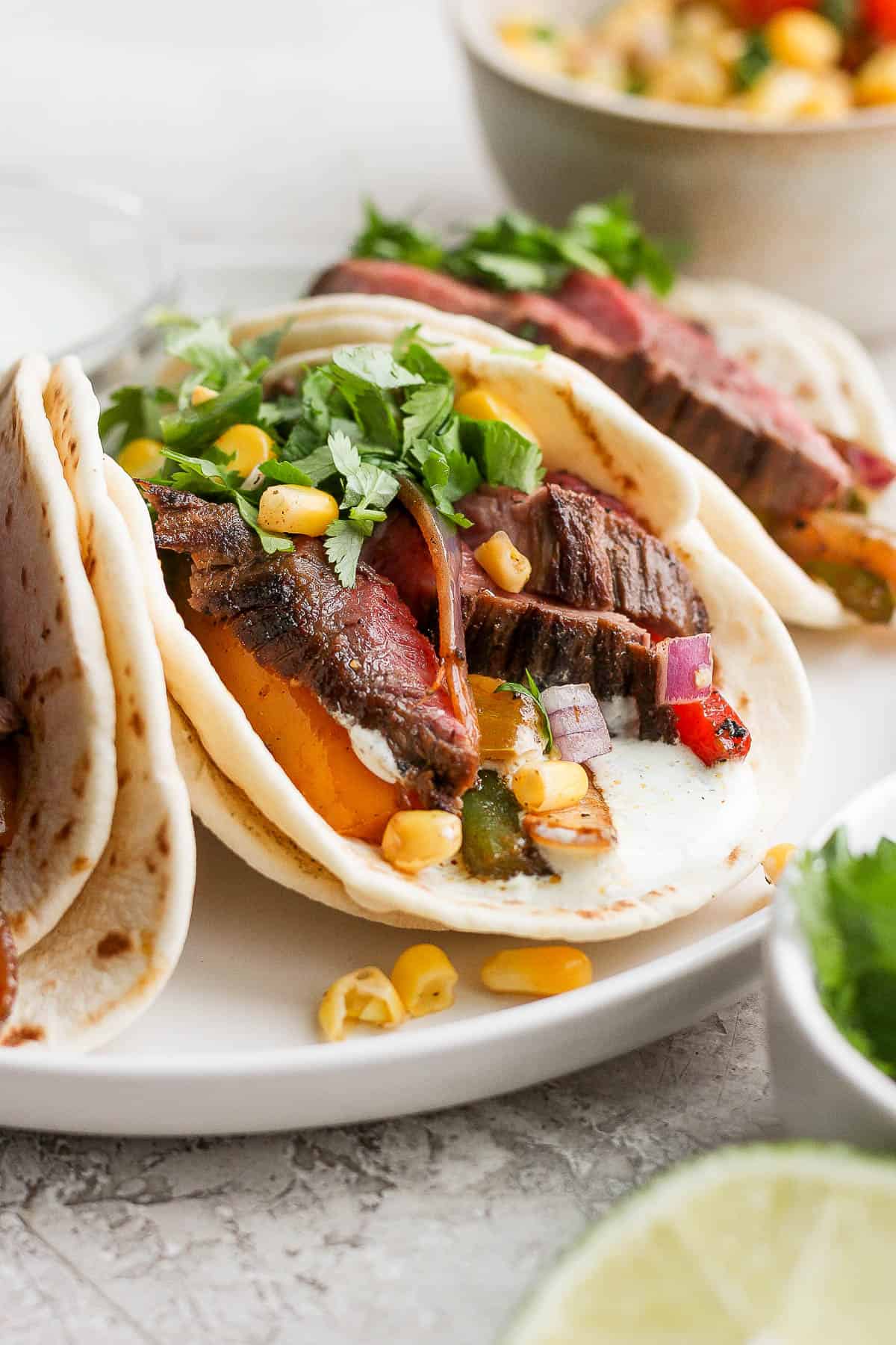 A steak fajita on a plate with cilantro lime sauce on the bottom of the fajita.