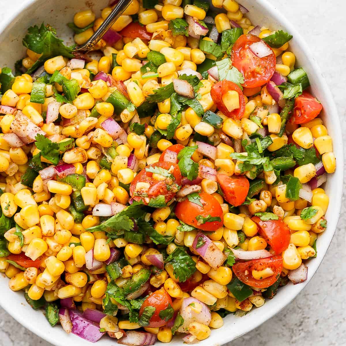 Bowl of fresh corn salsa with tomatoes and cilantro.