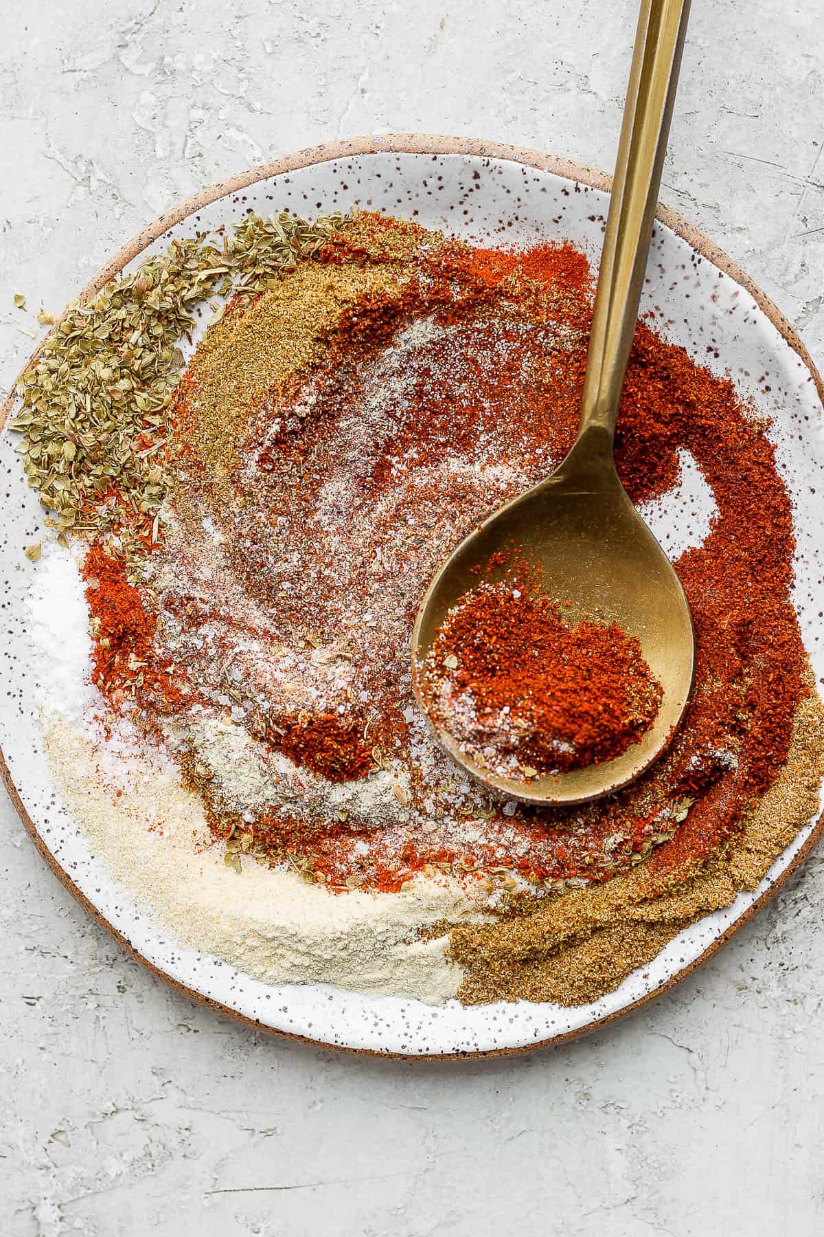 All of the ingredients in a shallow bowl with a gold spoon. 