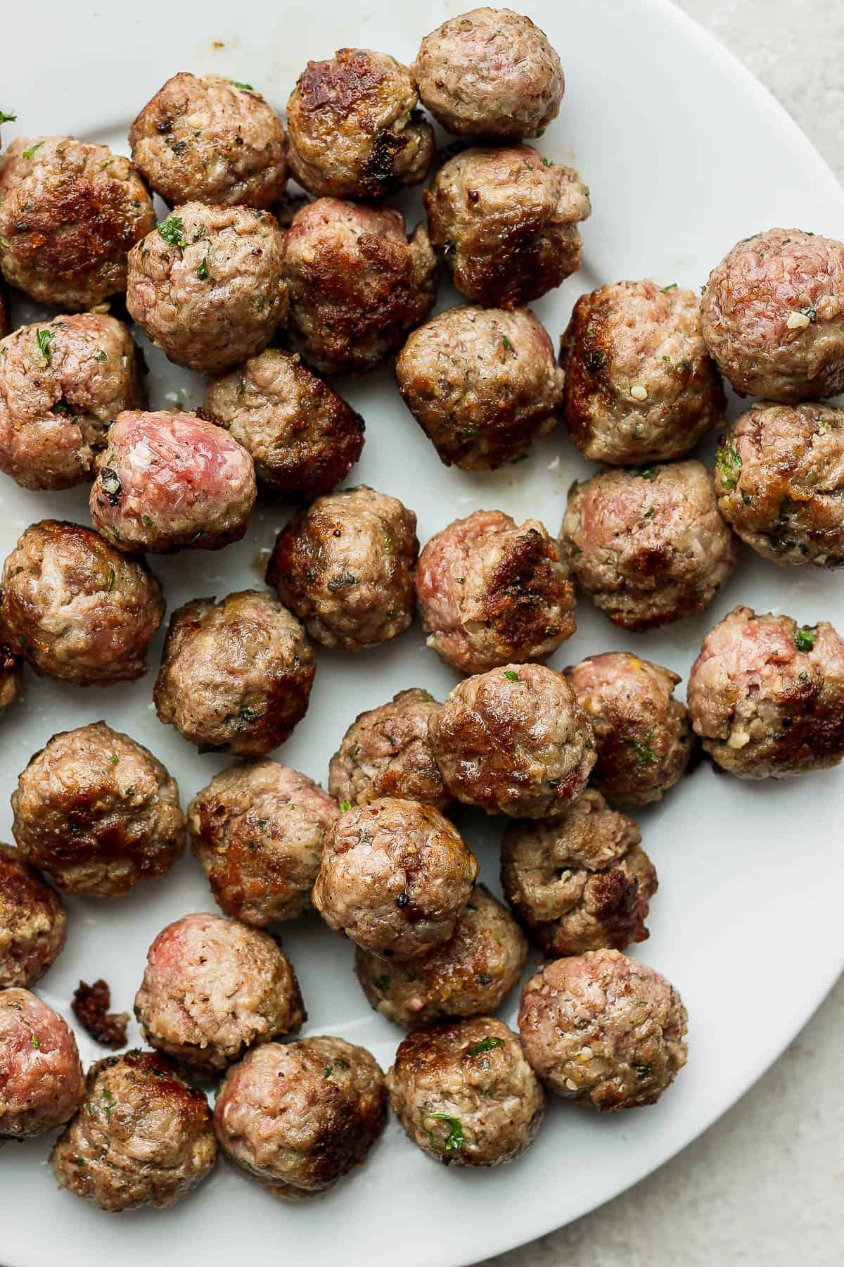Seared meatballs on a white plate.