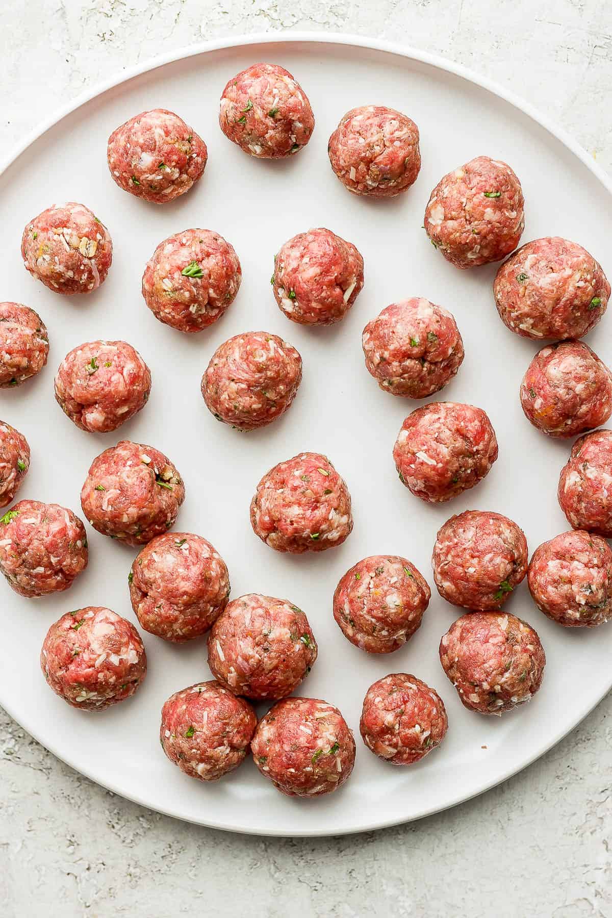 Fully formed meatballs on a white plate.