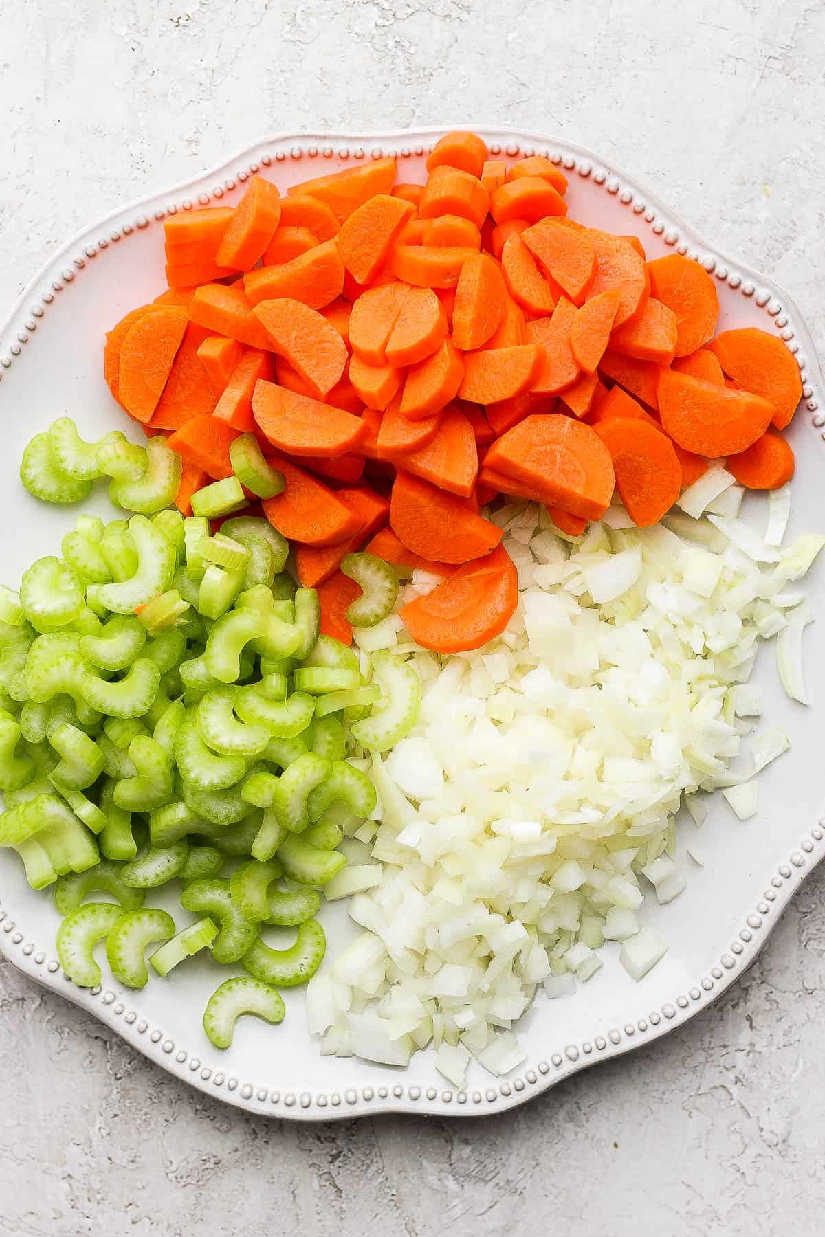 Chopped carrots, celery, and onion on a large plate.