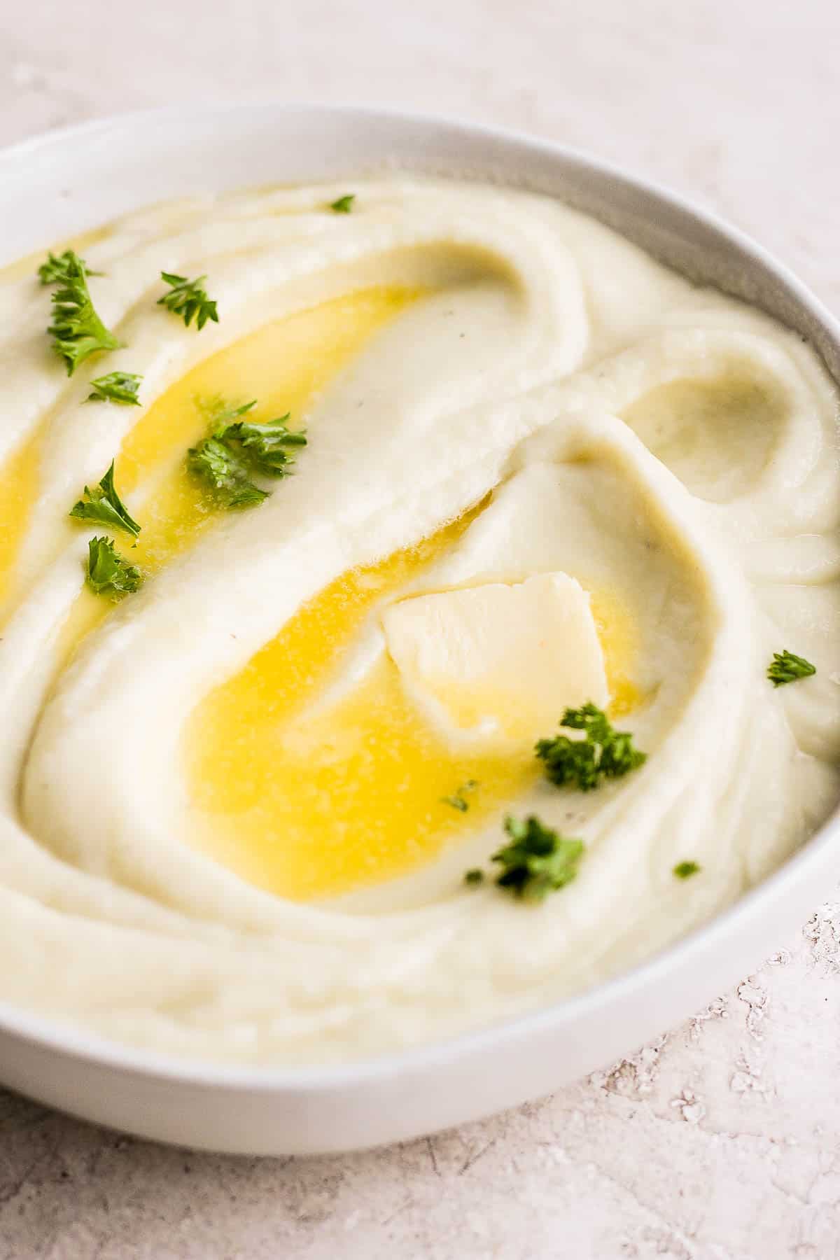Cauliflower mash in a bowl with butter on top.