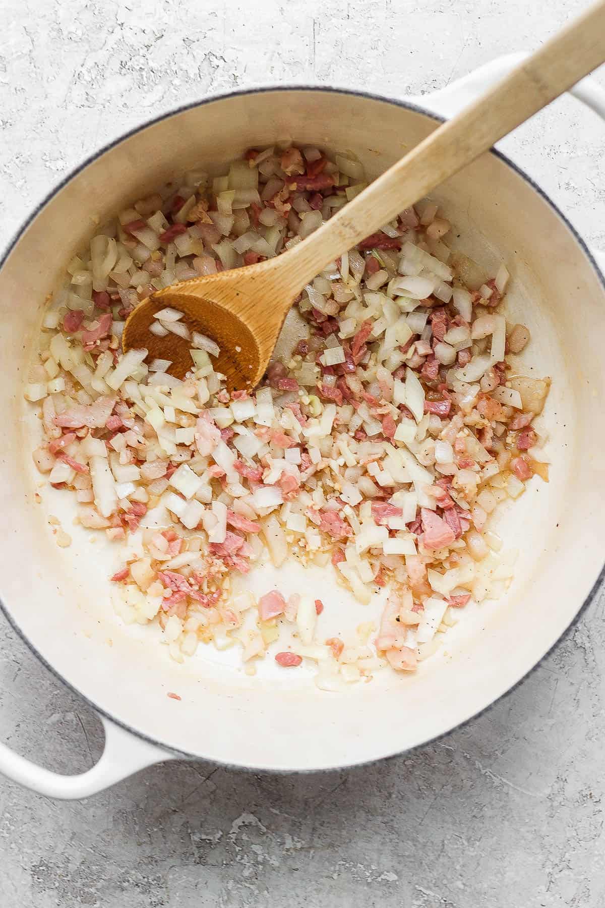 Pancetta, garlic, and onion sautéing in butter in a dutch oven.