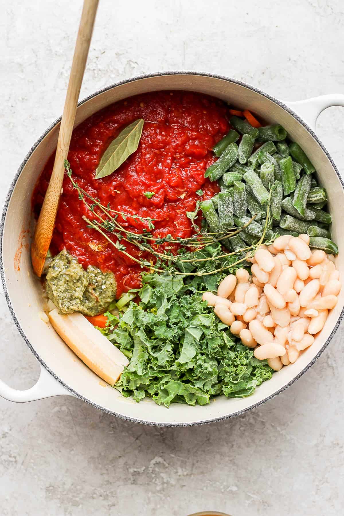 Crushed tomatoes, green beans, cannellini beans, kale, pesto, parmesan rind, fresh thyme, bay leaf, and lemon zest added to the pot.