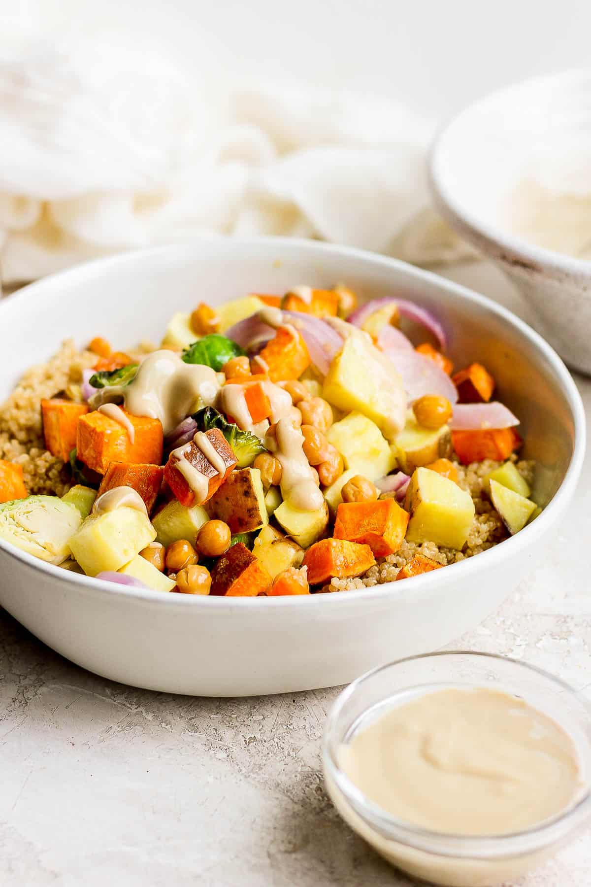 A quinoa bowl with coconut quinoa, roasted vegetables and peanut sauce drizzled on the top. 