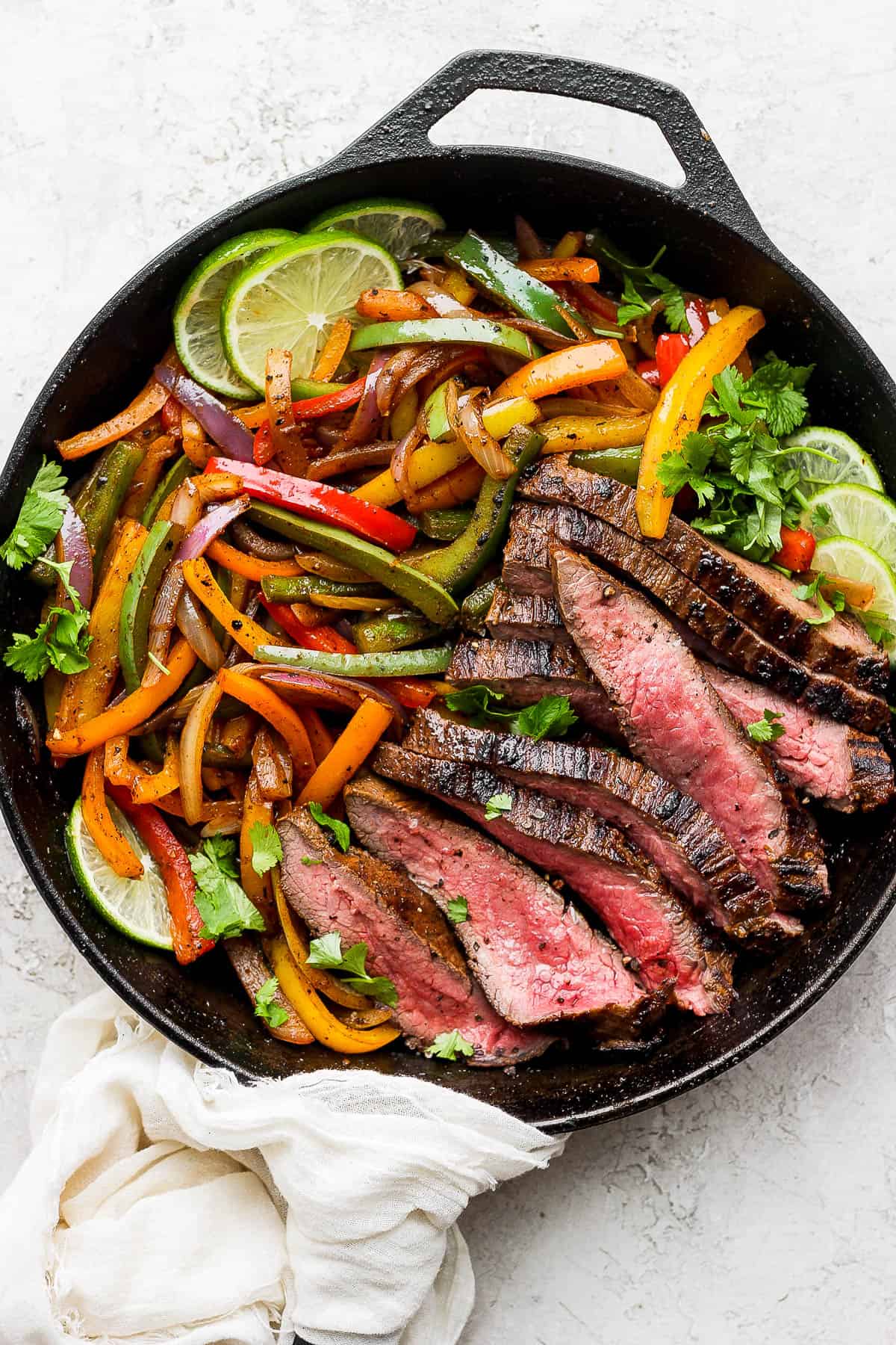 Strips of fajita steak and veggies in a cast iron skillet.