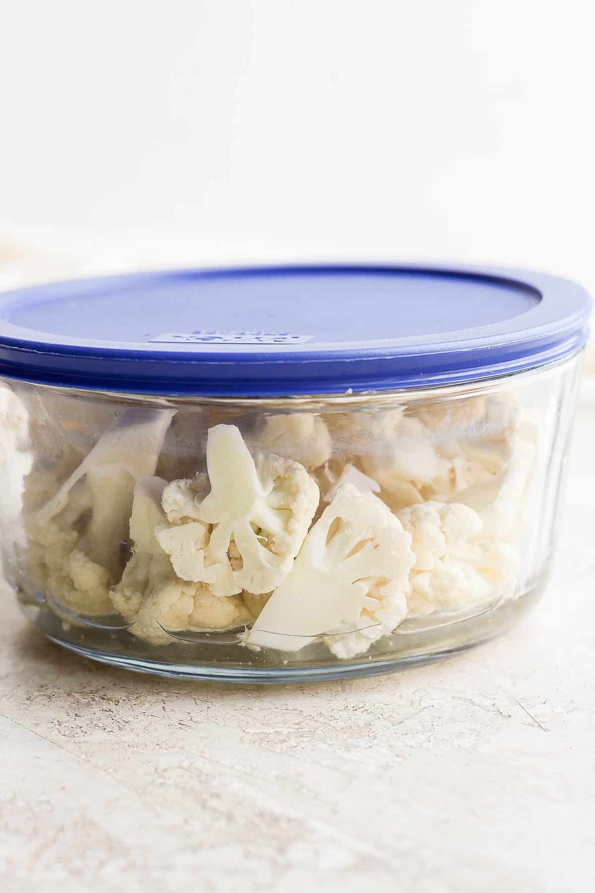 Cauliflower florets steaming in a microwave safe container.
