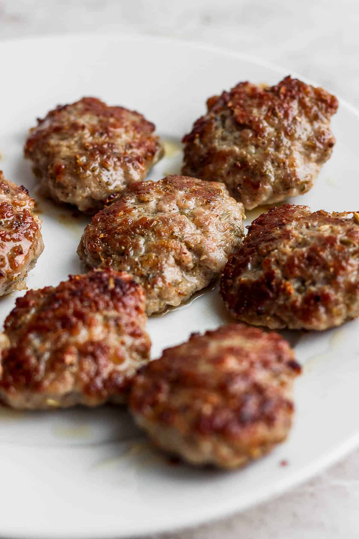 Cooked sausage patties on a white plate.