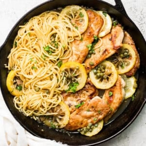 Cast iron skillet with chicken piccata pasta inside.