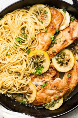 Cast iron skillet with chicken piccata pasta inside.