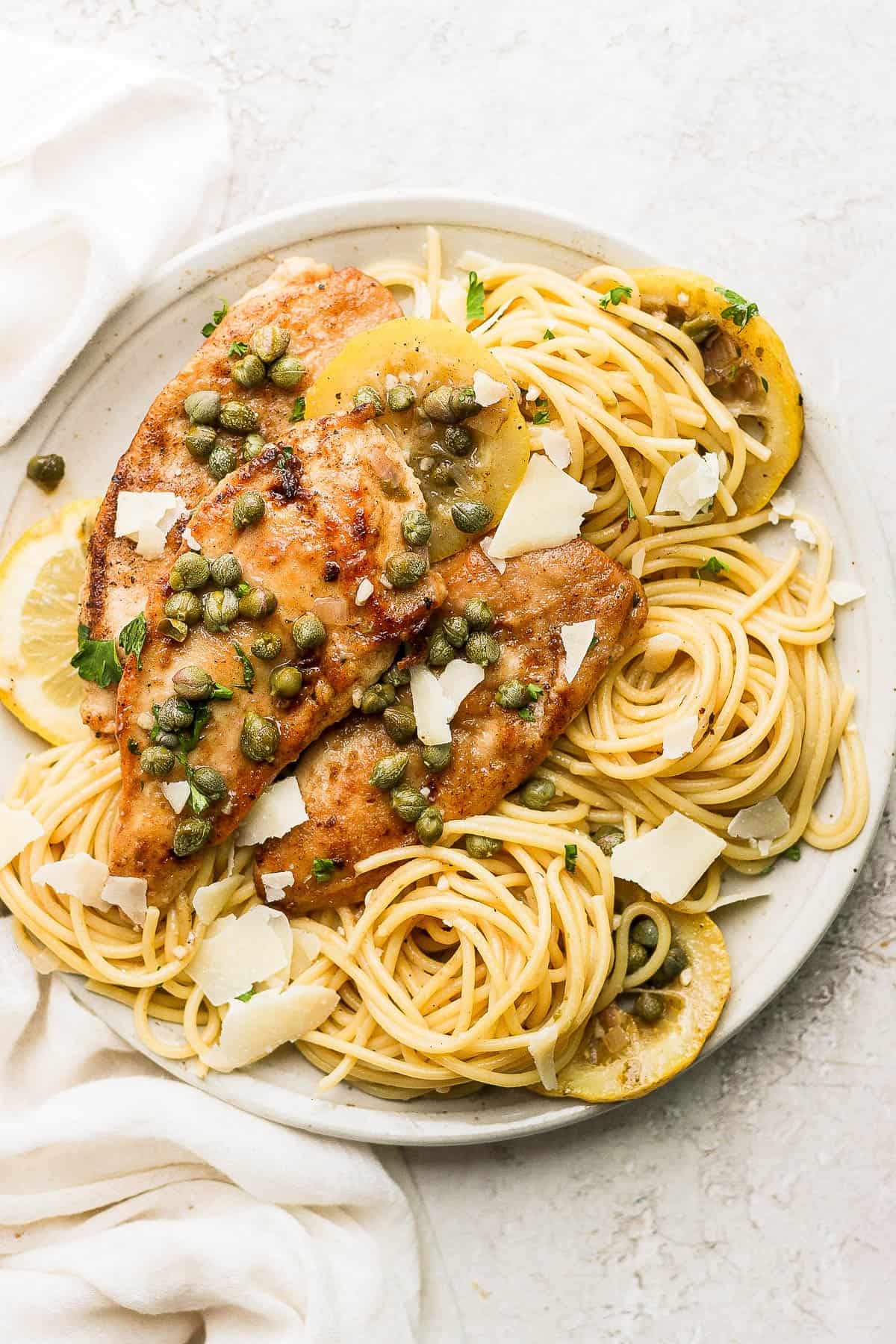 Chicken piccata pasta on a plate with parmesan on top.