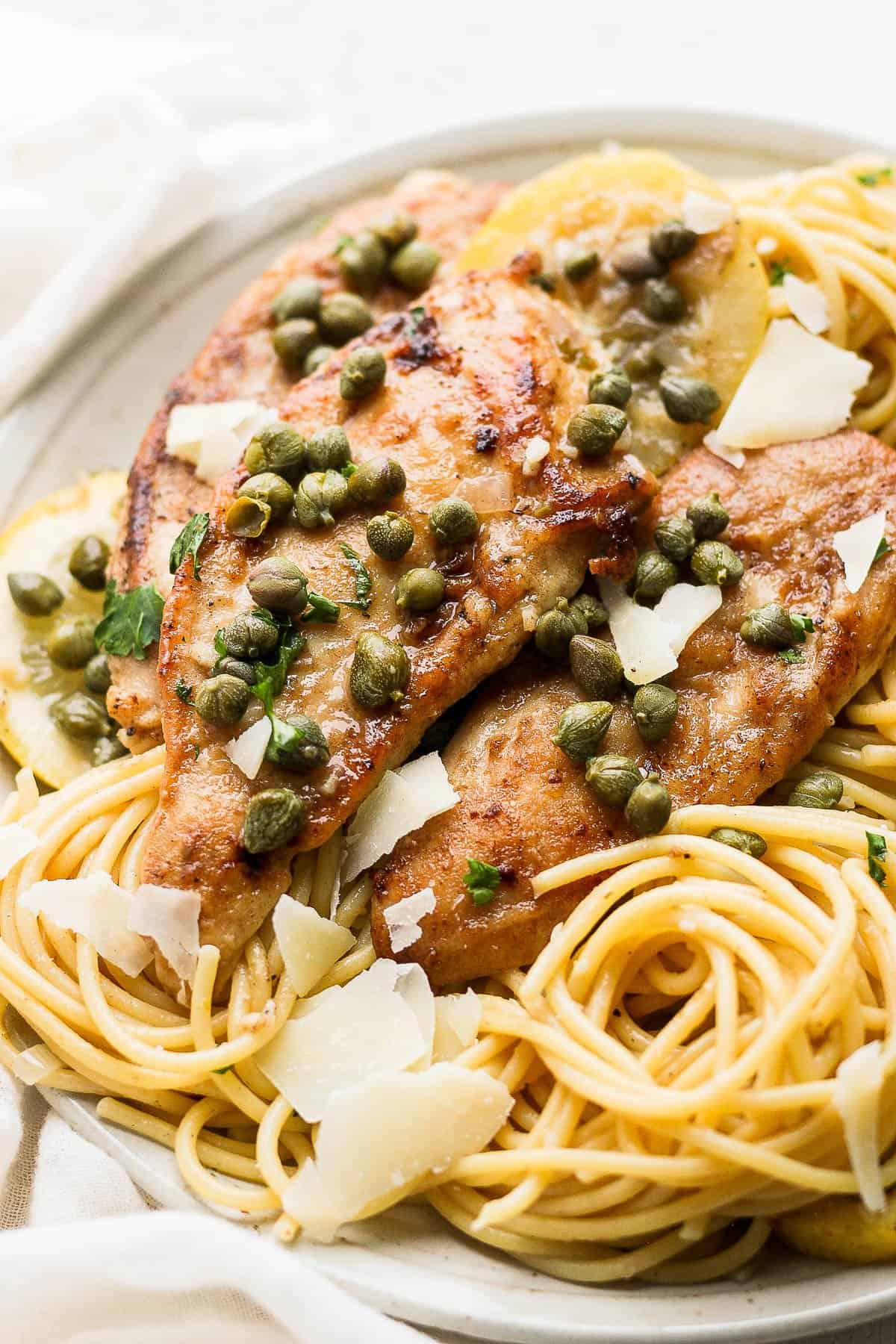 Another view of chicken piccata pasta on a plate after being garnished.