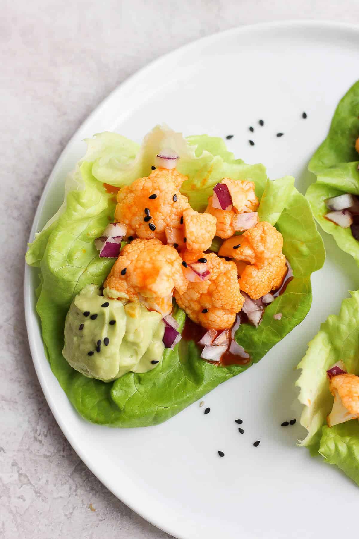 Buffalo cauliflower lettuce wrap on a white plate.