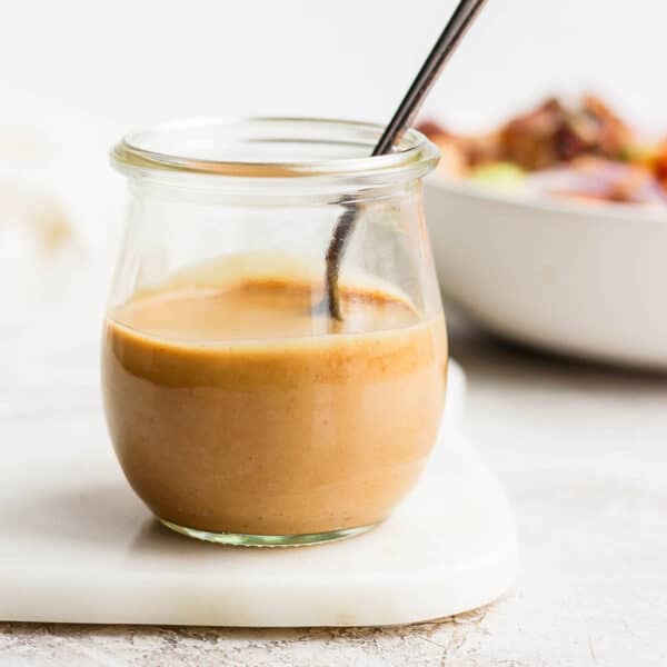 Jar of creamy peanut sauce with spoon sticking out.