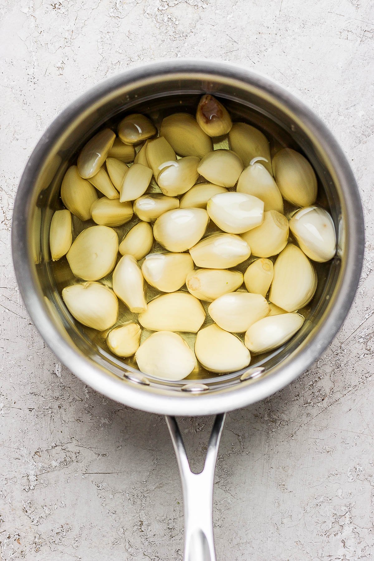 Peeled garlic cloves and olive oil in a small saucepan.