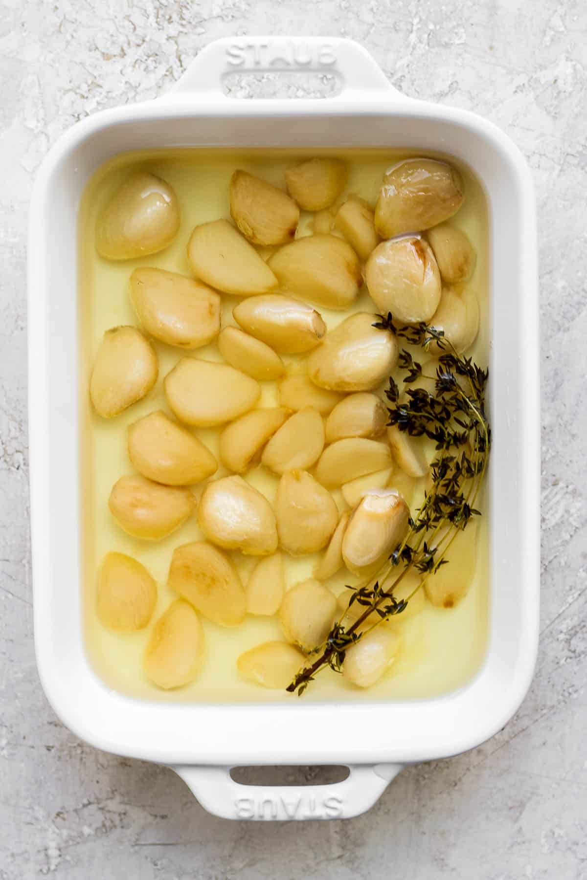 Garlic confit in a baking dish after baking in the oven.